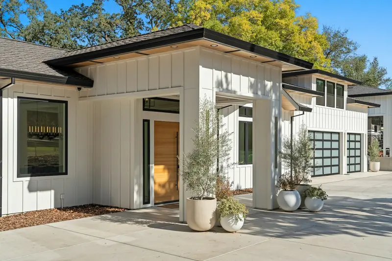 Modern white board and batten home with a glass garage door