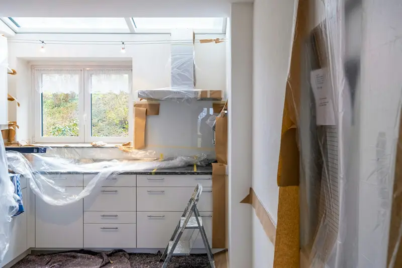 Kitchen mid renovation with cabinets and counters covered in protective plastic