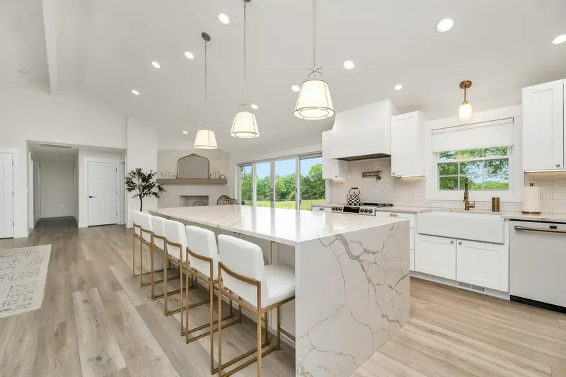 Bright kitchen with a white waterfall island, bar stools and pendant lights